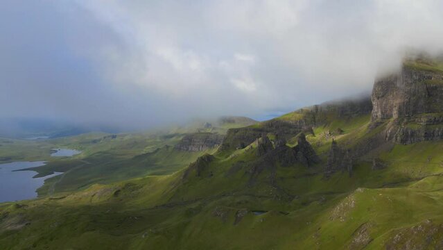 Aerial fly over above the Old man of Stor on the Isle of skye through the clouds with sunbursts during sunris