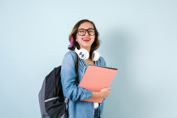 Obraz premium Young Hispanic student teen girl woman holding books with glasses over isolated blue background in Latin America