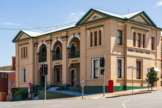 A two story historic building on a sloping corner block with traffic lights in front in Gympie