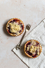 Two home baked plum crumble tarts with a fork