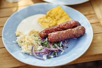 Romanian cuisine, traditional sausage called mici or mititei served with brynza, red onion and mamaliga