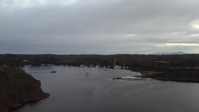 Aerial: Drone tracking a round a harbour full of boats in Tasmania, Australia