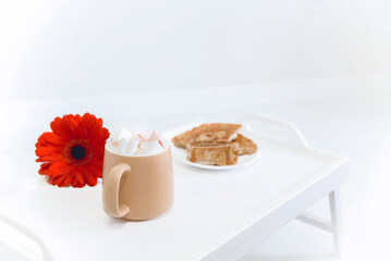 a cup of coffee with marshmallows with breakfast and an apple on a white tray on a white background, a feeling of tenderness, morning and security, selective focus