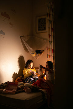Silhouette shot of two girls playing in the dark room on the bed
