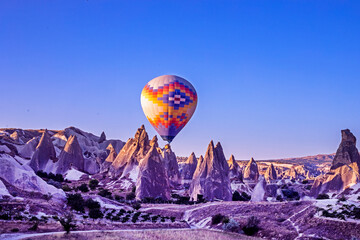 hot air balloon in the blue sky in front of bizarre mountain silhouettes in the Cappadocia valley...