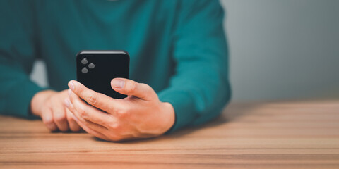 Closeup image of a man holding and using mobile phone or smartphone in room.
