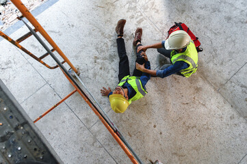 First aid support accident at work of builder worker in construction site. Accident falls from the scaffolding on floor, Foreman help employee accident with first aid bag. Top view image.