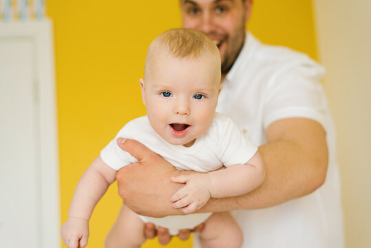 Positive cheerful dad holds his son in his arms. close-up photo of the baby
