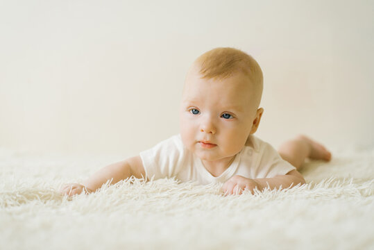 A five-month-old baby is lying on his stomach on the bed. The concept of caring for a baby