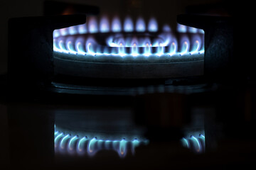 gas flames from a gas stove with reflections in the dark