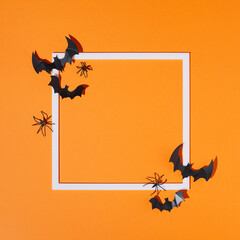 Creative layout made of bats silhouettes, spiders and frame on orange background. Minimal flat lay....