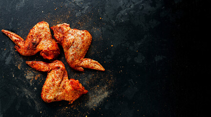 Raw chicken wings marinated in paprika and curry. Copy space. Raw meat on a dark background, top...