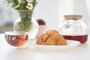 Transparent glass Cup of tea in nature. The concept of breakfast in the backyard of the house. Early morning, tea and kettle. In the cup you can see the reflection of the sky and a one-story house.
