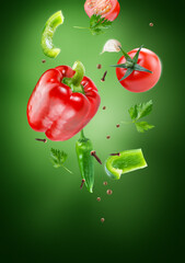 red pepper with tomatoes in group flying on air stream on dark green background