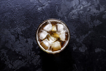 Glass with lemonade and ice. Top view. Copy space. A glass of beer on a dark concrete background.