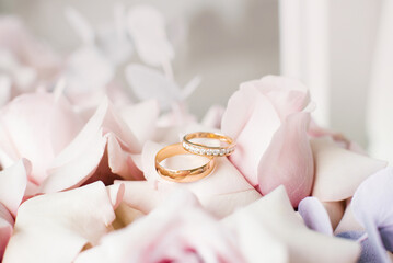 Gold wedding rings lie on delicate pink roses close-up