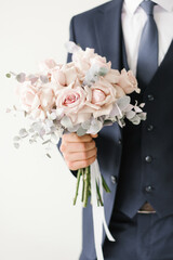 Stylish wedding bouquet of delicate pink roses in the hands of the groom close-up