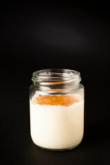 Homemade rice pudding in a glass pot over a black background