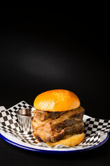 Beef rib burger on a white plate over a black background