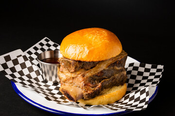 Beef rib burger on a white plate over a black background