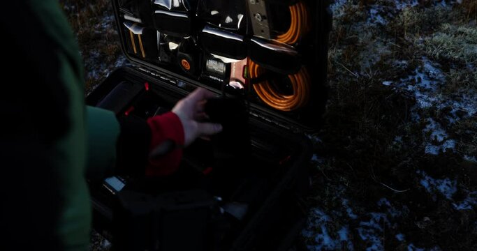 Man taking out large tele lens to put on camera from hard flight case, close up