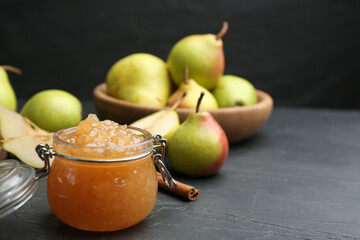 Tasty homemade pear jam and fresh fruits on black table. Space for text