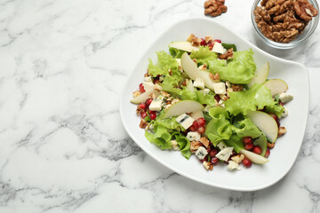 Tasty salad with pear slices and walnuts on white marble table, flat lay. Space for text