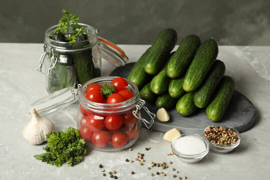 Pickling jars with fresh ripe vegetables and spices on grey table