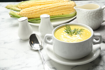 Delicious creamy corn soup served on white marble table