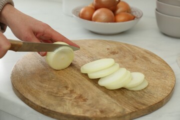Woman cutting white onion into rings at countertop, closeup