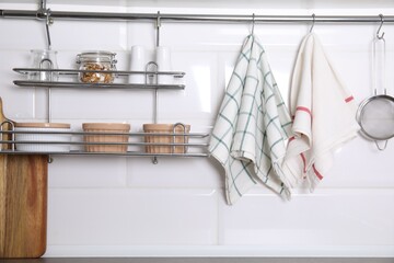 Different kitchen towels hanging on hook rod and shelves with ramekins indoors