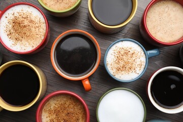 Many different cups with aromatic hot coffee on wooden table, flat lay