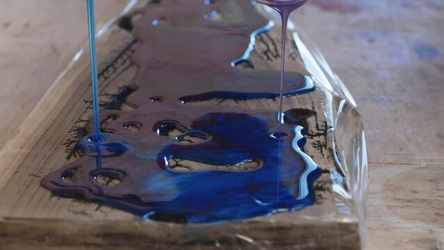 Process making of a craft resin and wood cutting board. Liquid epoxy is poured on the surface.