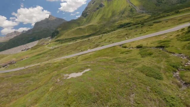 Fastest aerial cinematography over road running amidst vast endless green valley at Silvretta Reservoir in Austria.