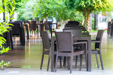 Fototapeta na wymiar Outdoor tables and chairs, empty beach restaurant table. Rattan style furniture in the restaurant