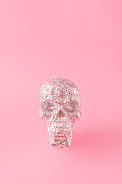 Skull in aluminium foil on pastel pink background. Minimum pink Halooween concept.