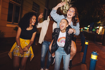 Young woman laughing hysterically while piggybacking her friend