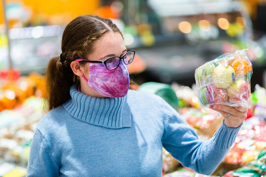 Woman Holding Up Pack Of Fresh Fruit Covered In Plastic, Grocery Shopping During Covid