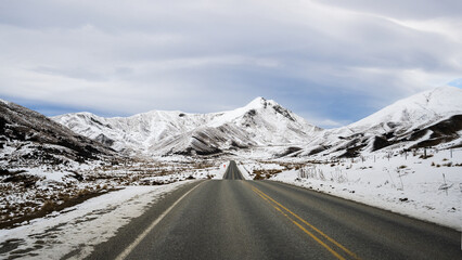 Road to Lindis Pass in winter, mountains covered in snow. South Island.