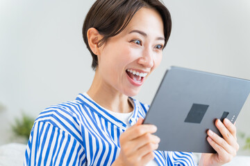 タブレットを横に持ち見る日本人女性