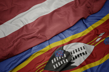 waving colorful flag of swaziland and national flag of latvia.