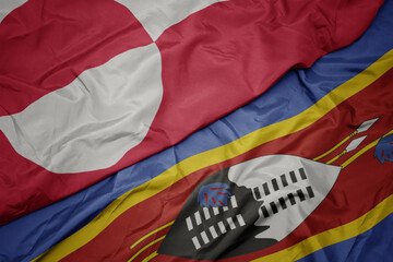 waving colorful flag of swaziland and national flag of greenland.