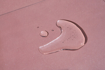 A drop of cosmetics or perfume on a pink background.