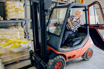 Machinery at warehouse and industry. A senior worker sitting in a forklift and lifting freight. © Dusan Petkovic