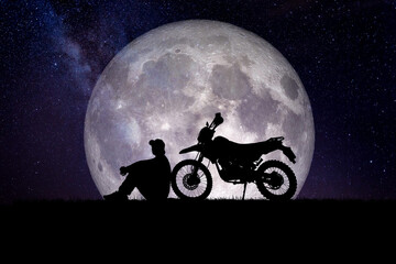 Man with a motocross motorcycle against the backdrop of the moon