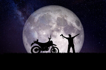 Man with a motocross motorcycle against the backdrop of the moon