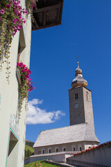 Old church and old houses with flowers at Lech am Arlberg, Austria, during summer, blue sky