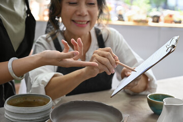 Happy young woman and middle aged woman creating handicraft crockery in workshop. Activity, handicraft, hobbies concept