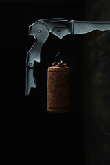 Metal corkscrew and wine stopper. Vertical photo on a dark background.