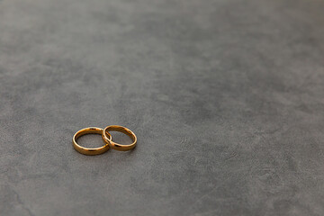 Will you marry me. Two golden wedding rings on concrete stone grey background. Engagement marriage...